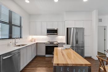 A kitchen with white cabinets and stainless steel appliances and a wooden table